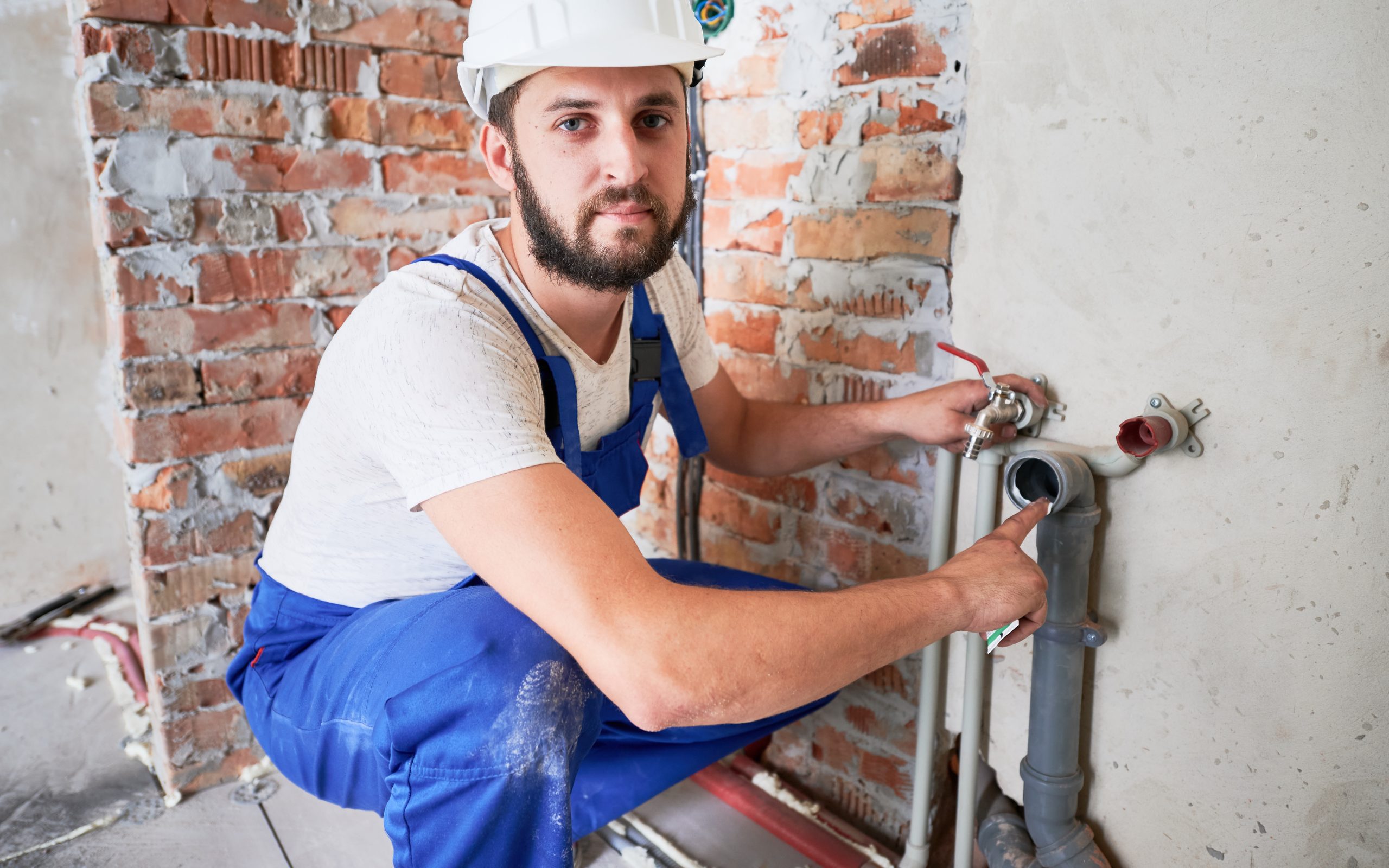 Bearded young man lubricating heating pipe.